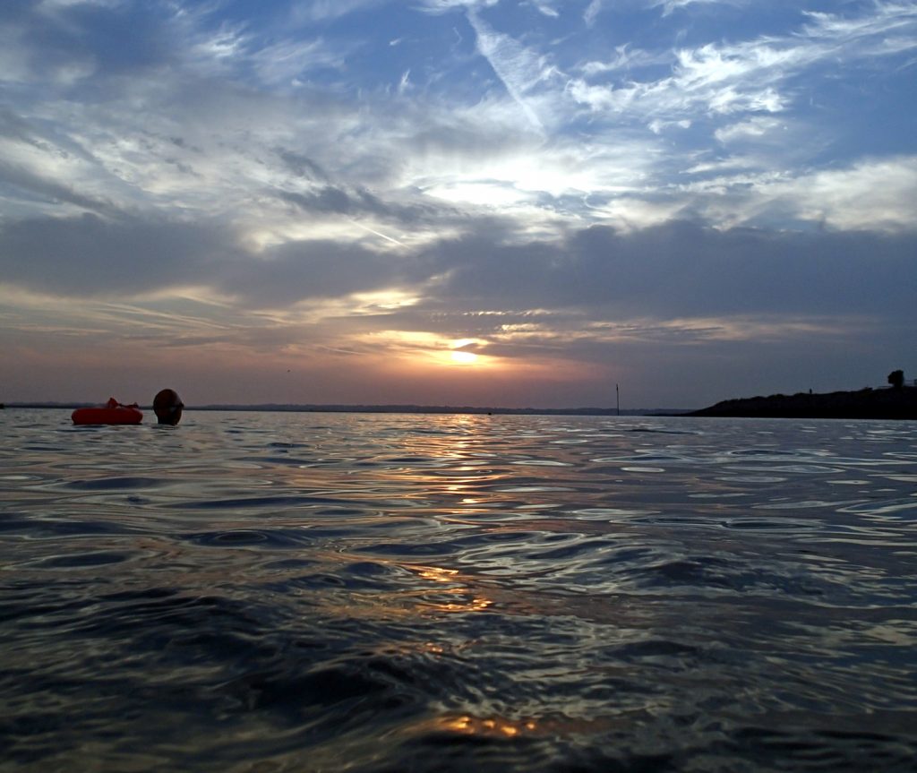 sunset on sea with head of swimmer