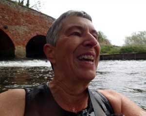 person in water in front of a bridge