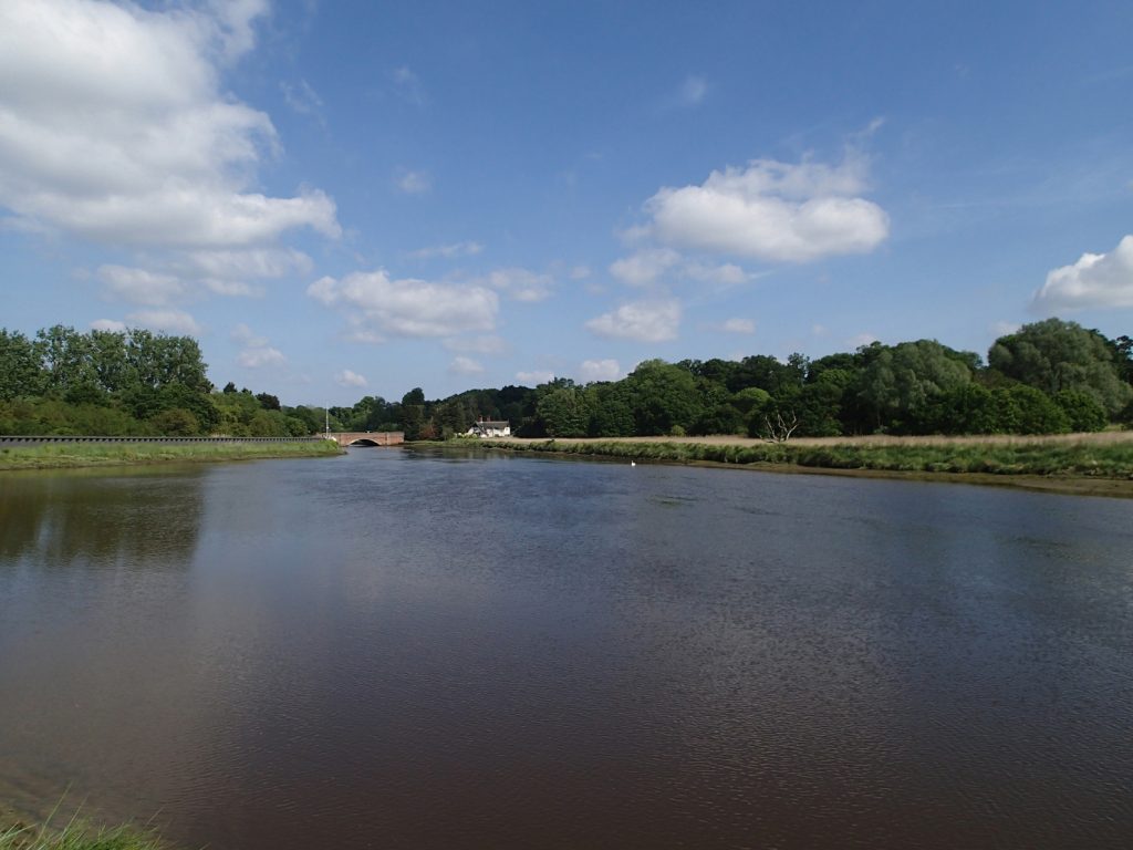 wide calm river with bridge in distance