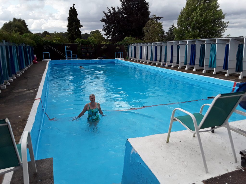 swimmer in lido with changing cubicles around