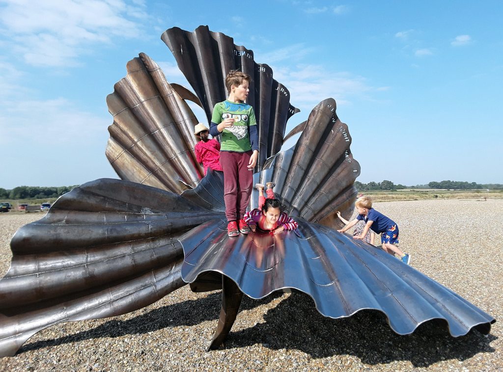 sculpture with children playing on it, on the beach