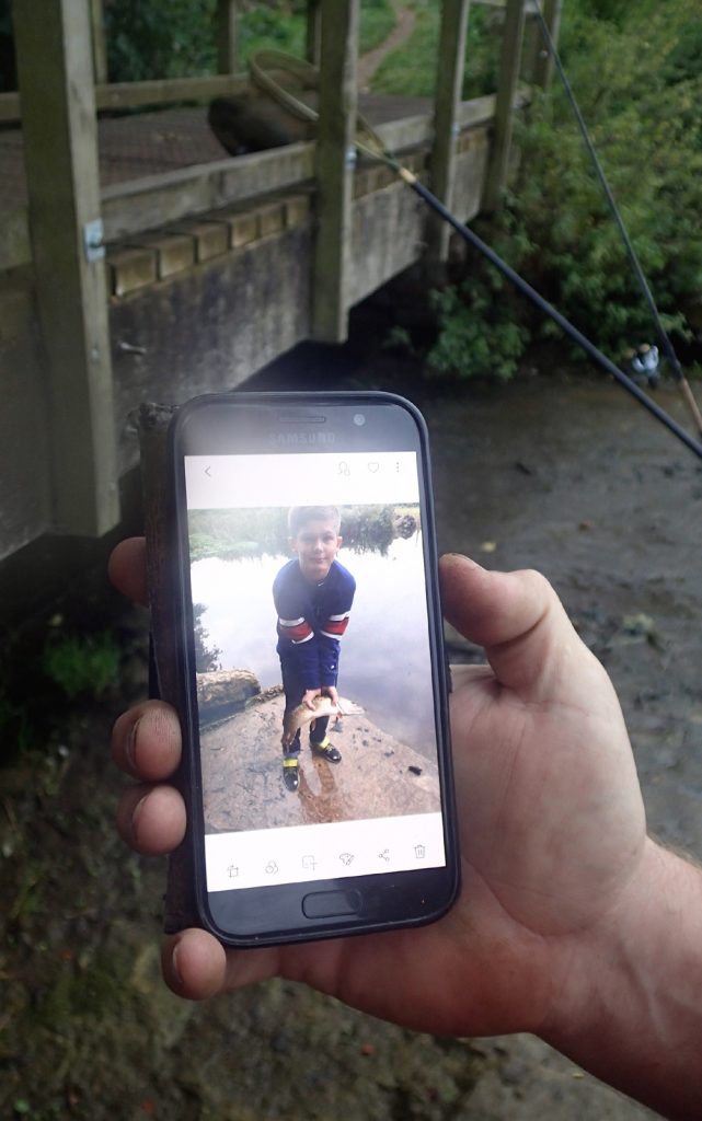 angler's phone with photo of boy holding fish