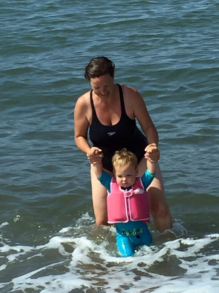 parent holding child in sea