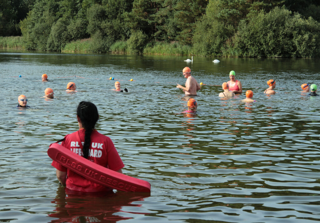 swimmers in water with lifeguard