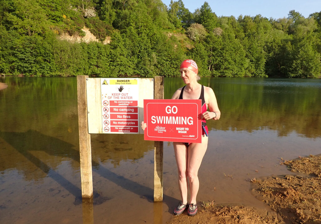 swimmer with Go Swimming sign in front of No Swimming sign at lake