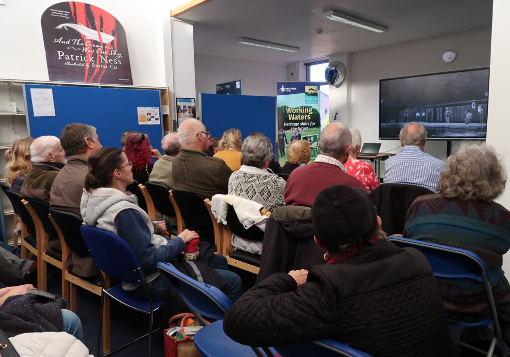audience watching film screen with image of river baths