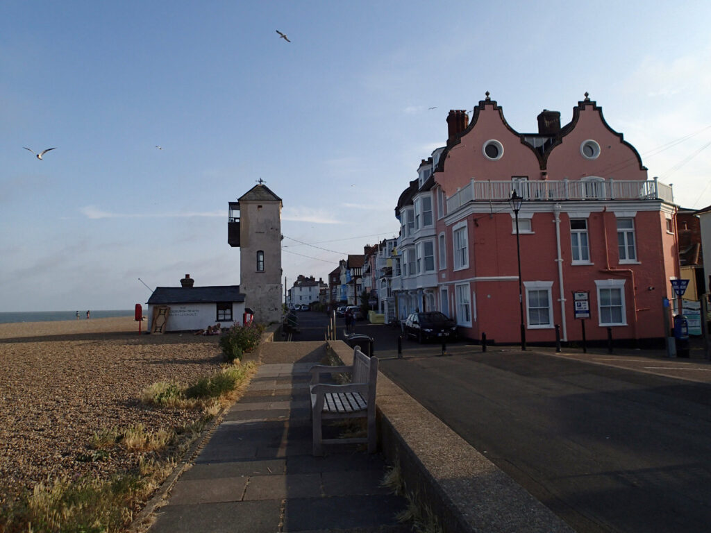 one of the Aldeburgh beach towers with pink seafront houses and the sea