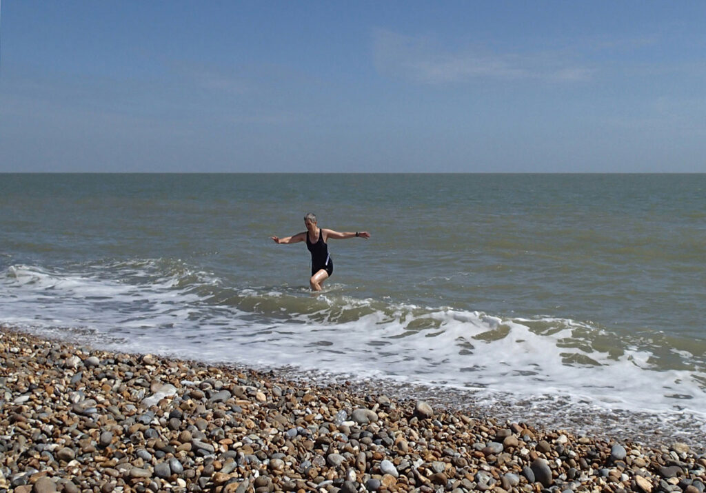swimmer coming out of the sea onto shingle beach