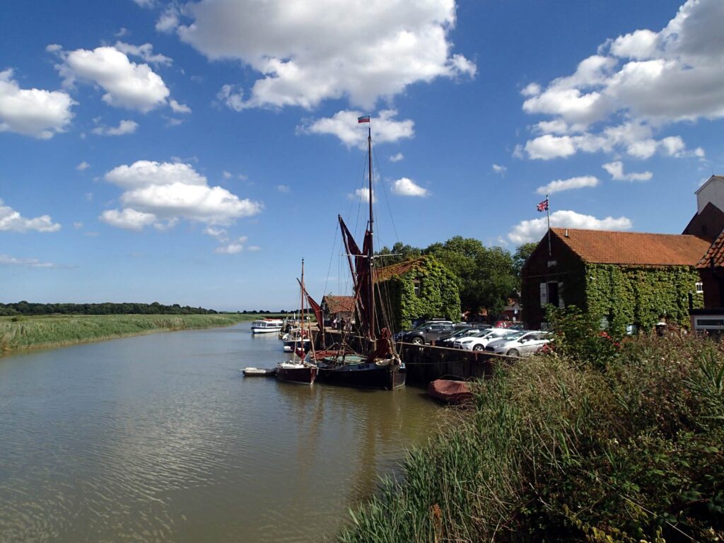 river with Thames barge and some buildings, blue sky with white clouds
