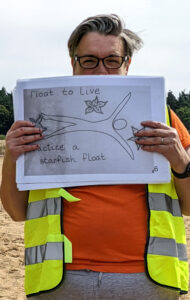 woman in hi vis holding A3 sheet with image of starfish Float to Live