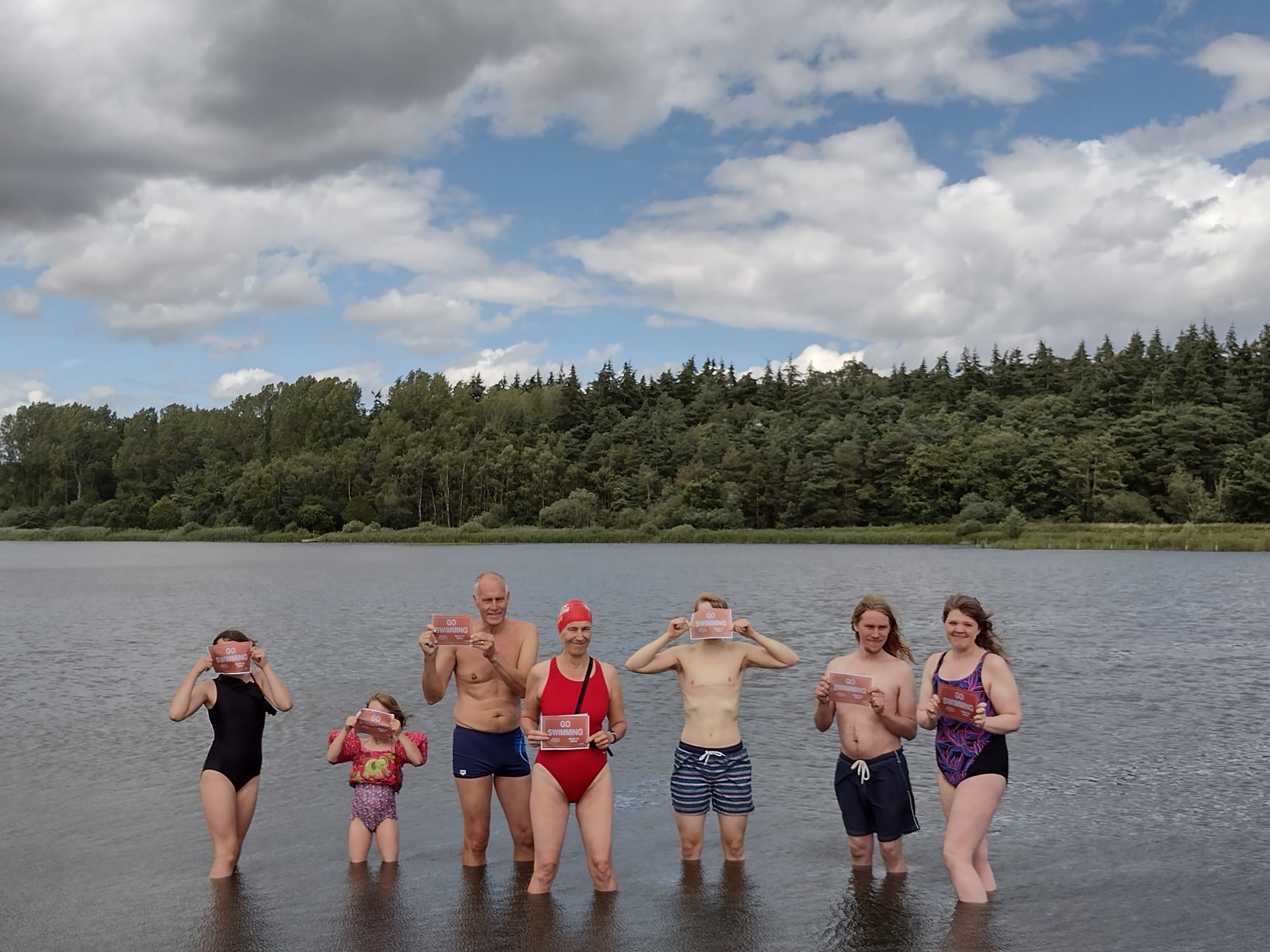 swimmers in a lake holding placards saying 'Go Swimming'