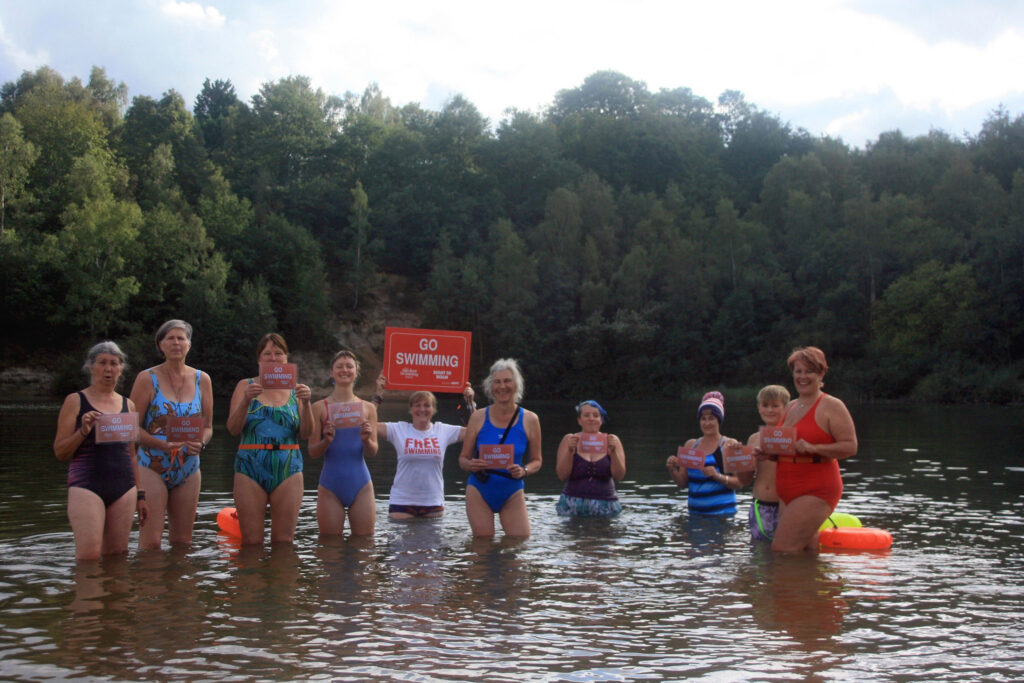 swimmers in the lake with banners reading 'Go Swimming'