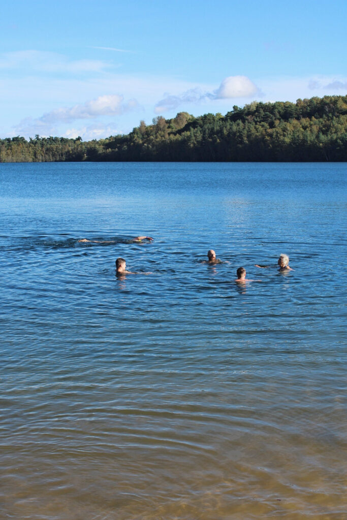Swimmers in large lake, water blue reflecting blue sky