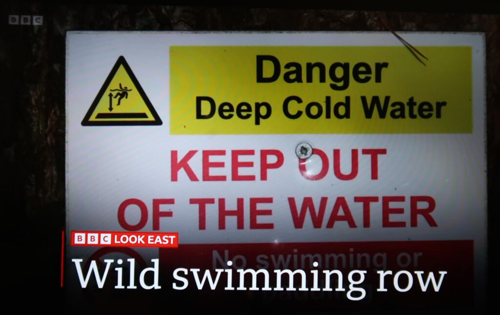 Sign reading “Danger Deep Cold Water, KEEP OUT OF THE WATER, no swimming or paddling. BBC Look East: Wild swimming row”
