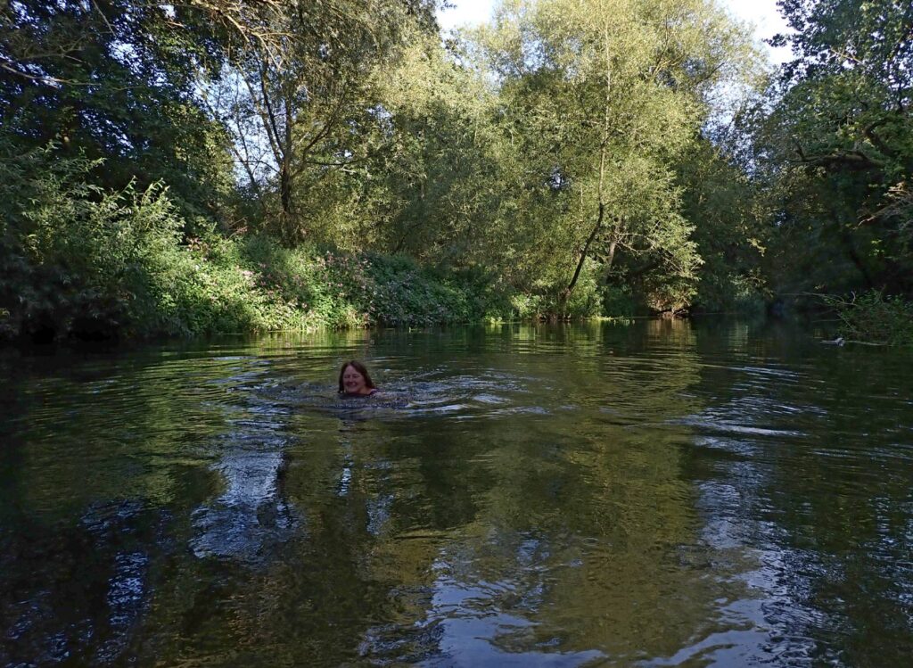 swimmer in a river shaded by trees
