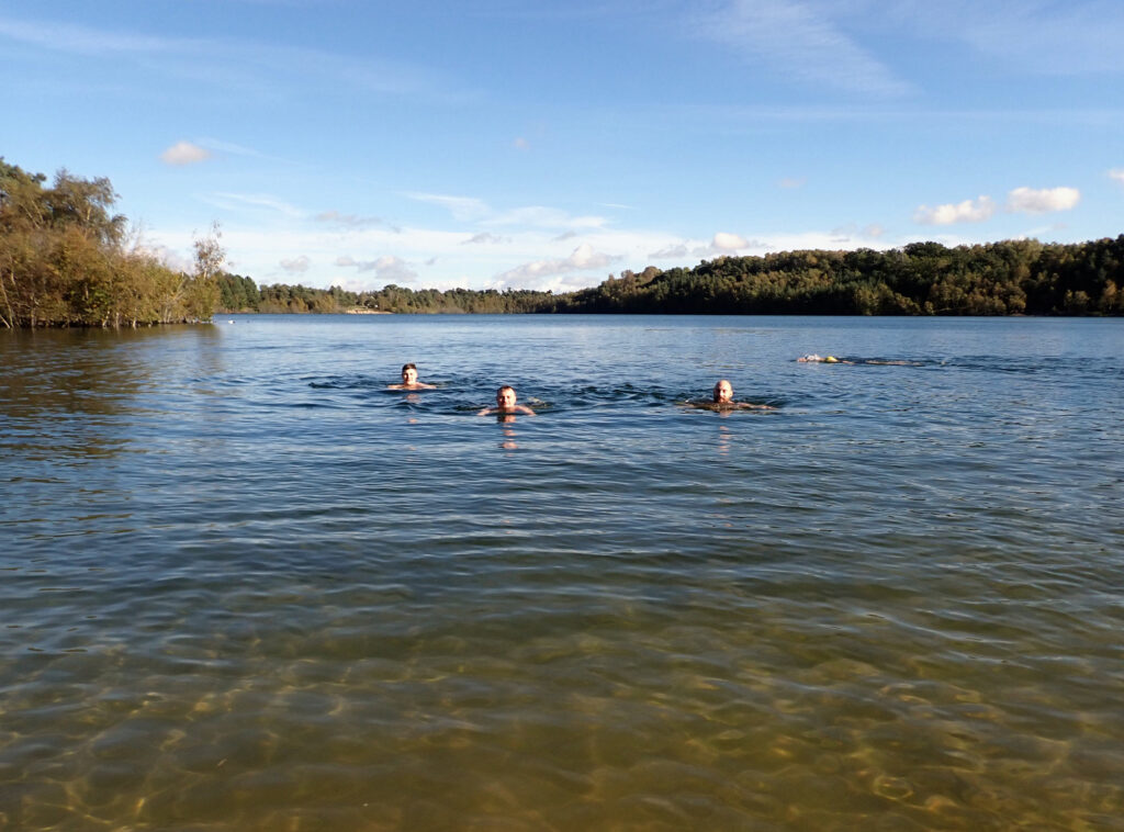 blue skies and water, sandy shallow edge, swimmers in lake
