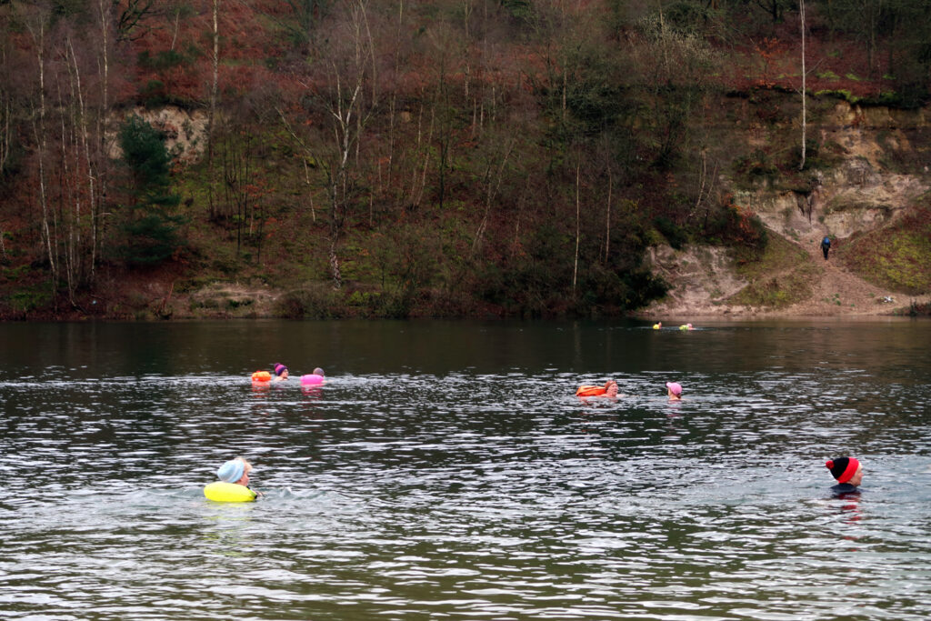 swimmers in the water at Brickyard Lake, cliff rising behind the water