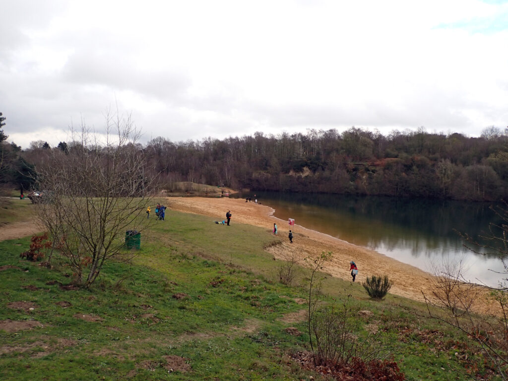 view from above down to Brickyard Lake, sandy beach, cliff behind the water